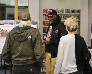 Museum presenter speaking with visitors at a library exhibit
