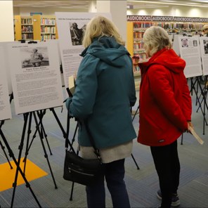 Two visitors reading picture exhibits inside a library
