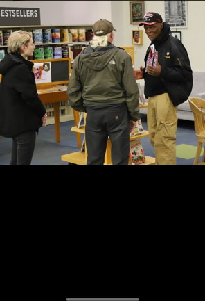 Presenter talking with two visitors near library shelves